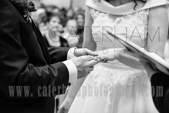 Surrey wedding photographer- St Paul's Church Addlestone- Groom puts the ring on Braids hand black and white